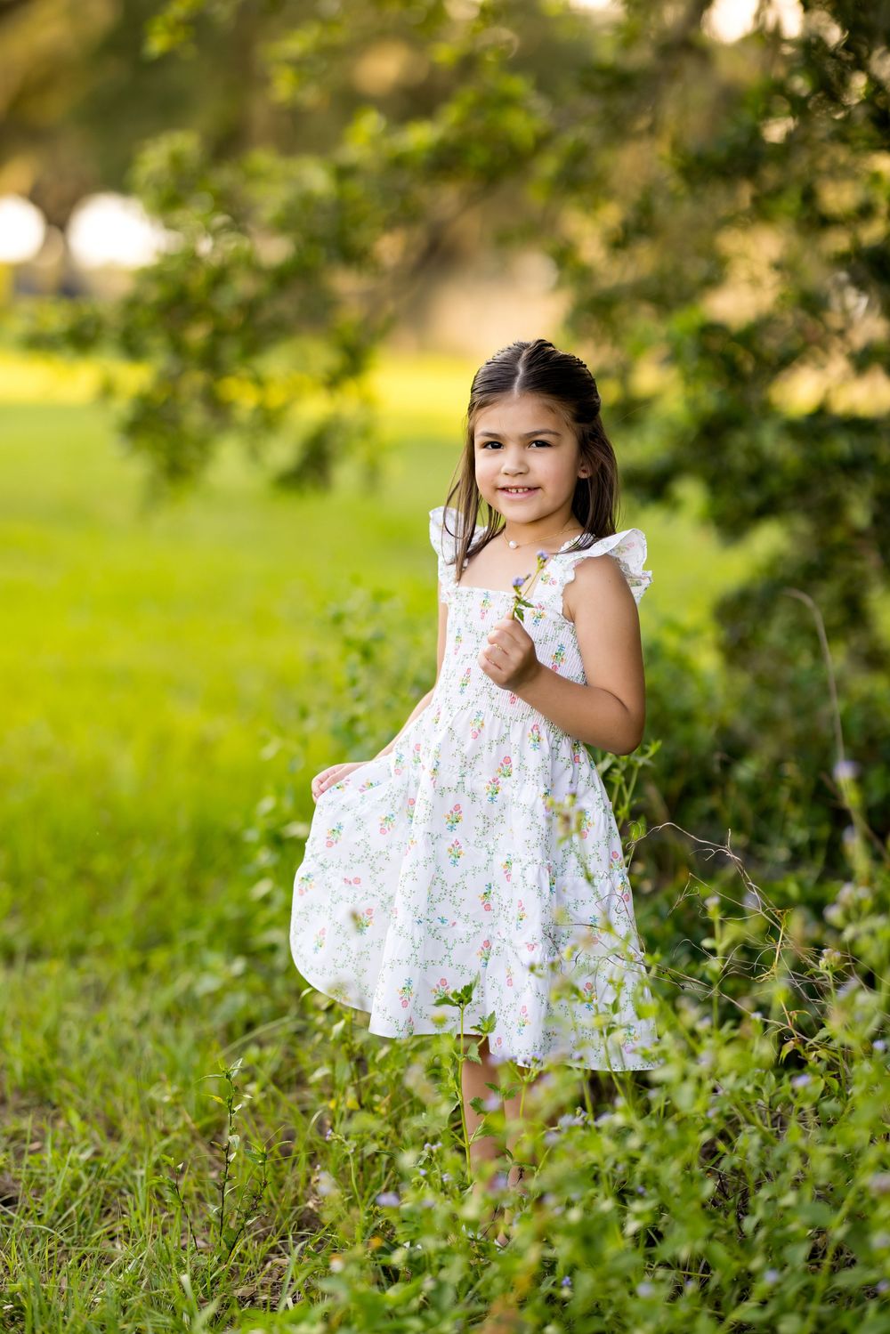 Young girl in a floral dress sitting among wildflowers during sunset. Photo by Dani De La Rosa, DigitalMyst Photography, Wesley Chapel FL