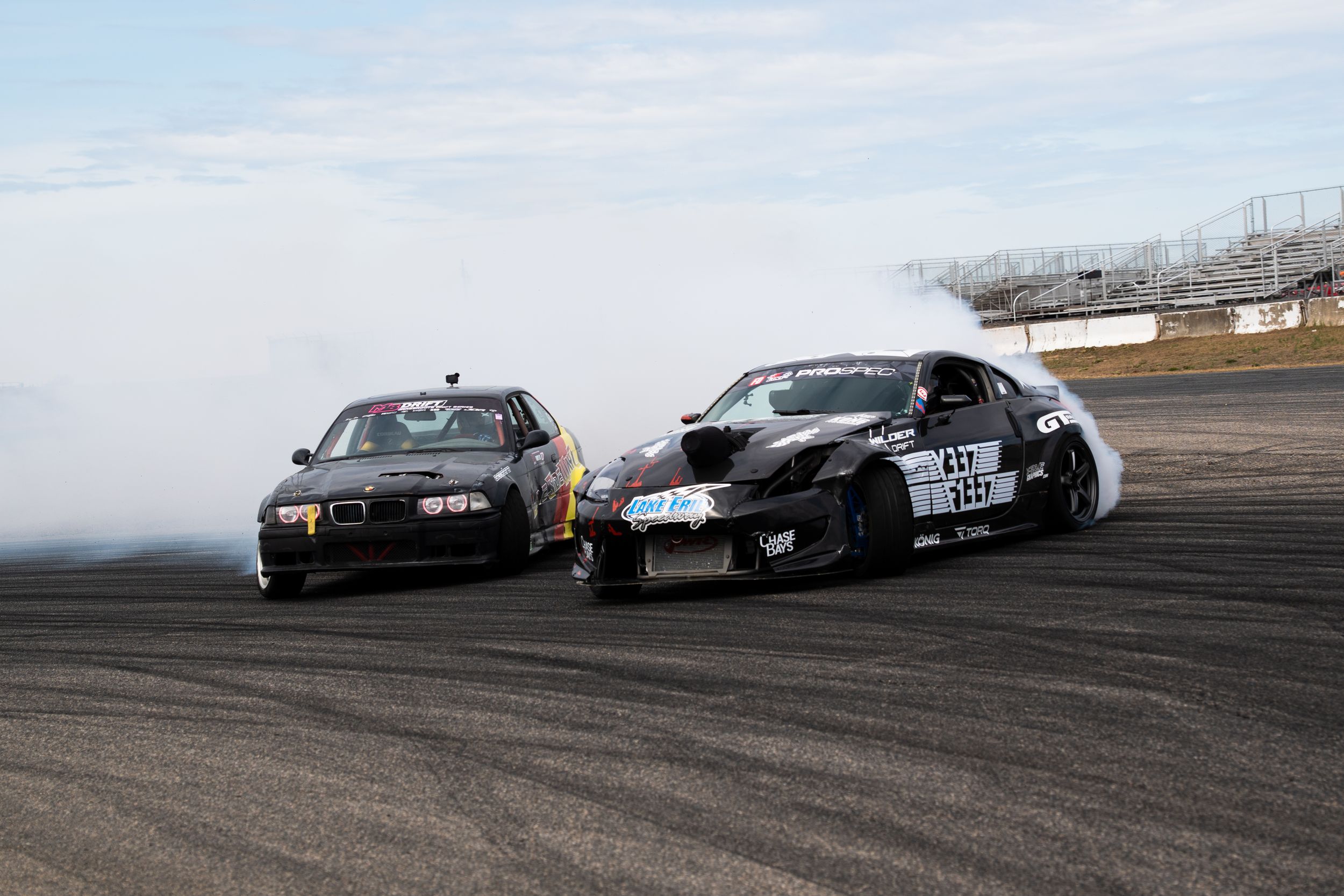 BMW and Nissan 350z drifting on track chasing each other at Rockngham Motor Speedway