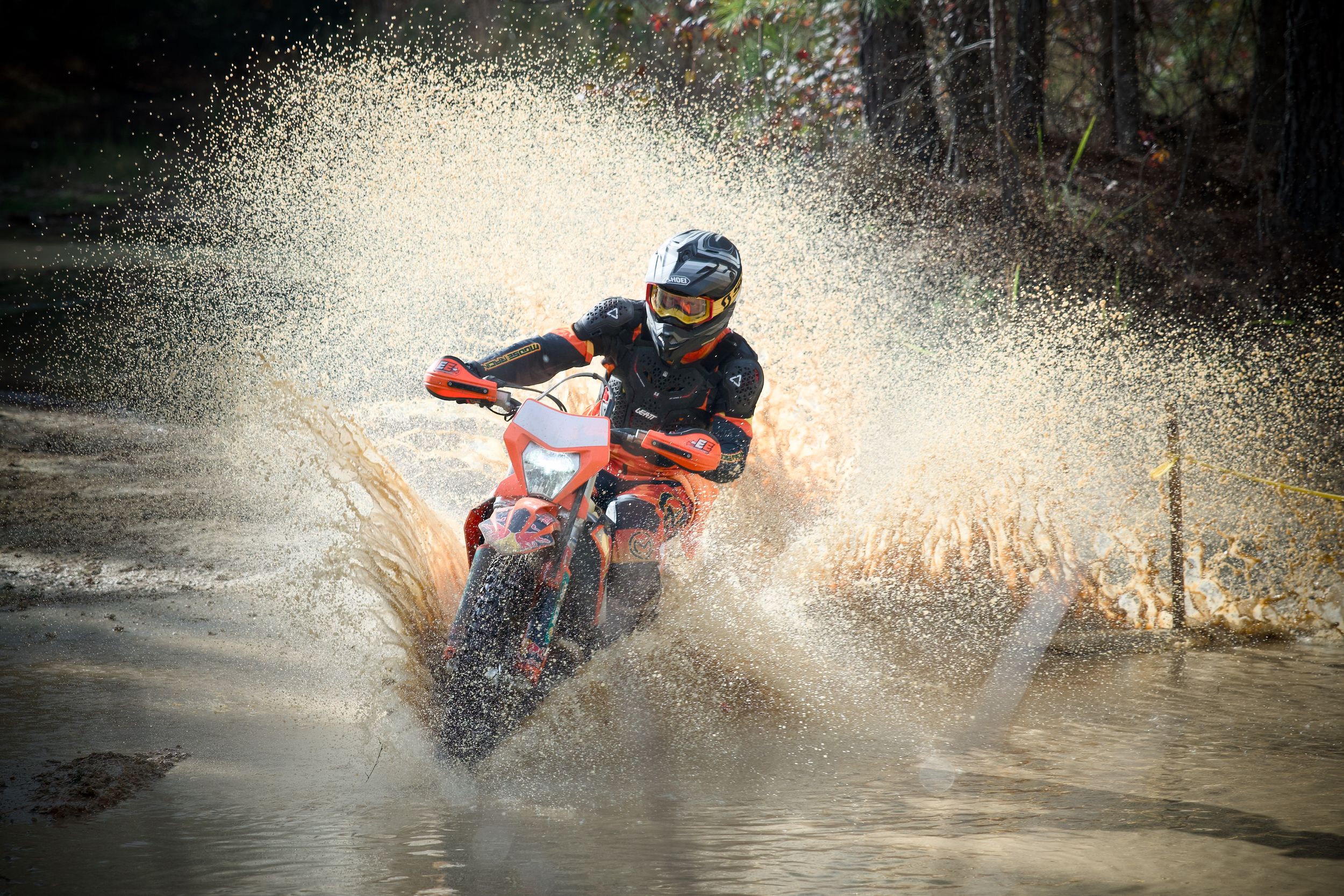 Dirt bikes splashing through water obstacles during an intense off-road race.