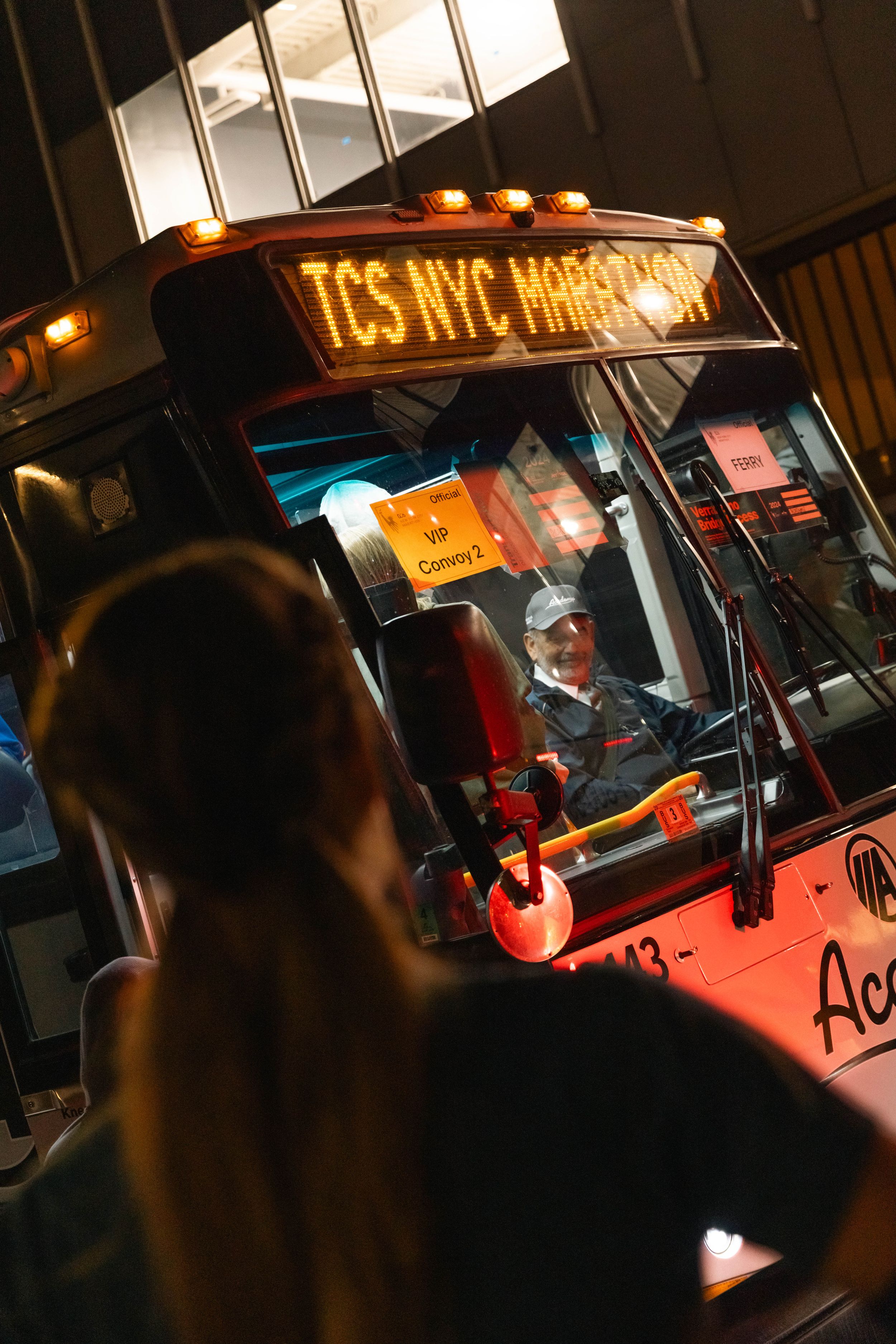 NYC transit bus with illuminated display at night time.