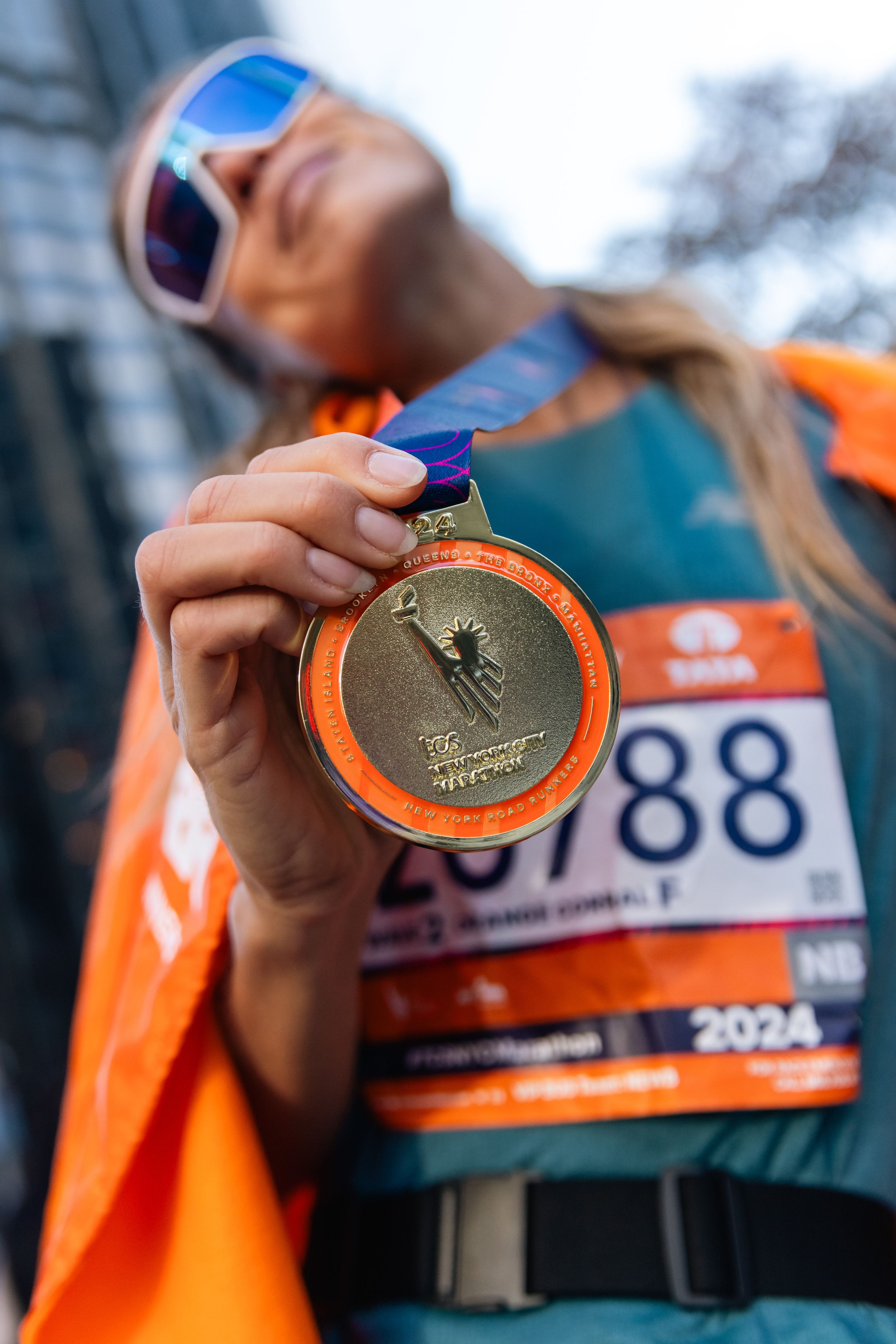 Runner displaying marathon finisher medal with race number visible.
