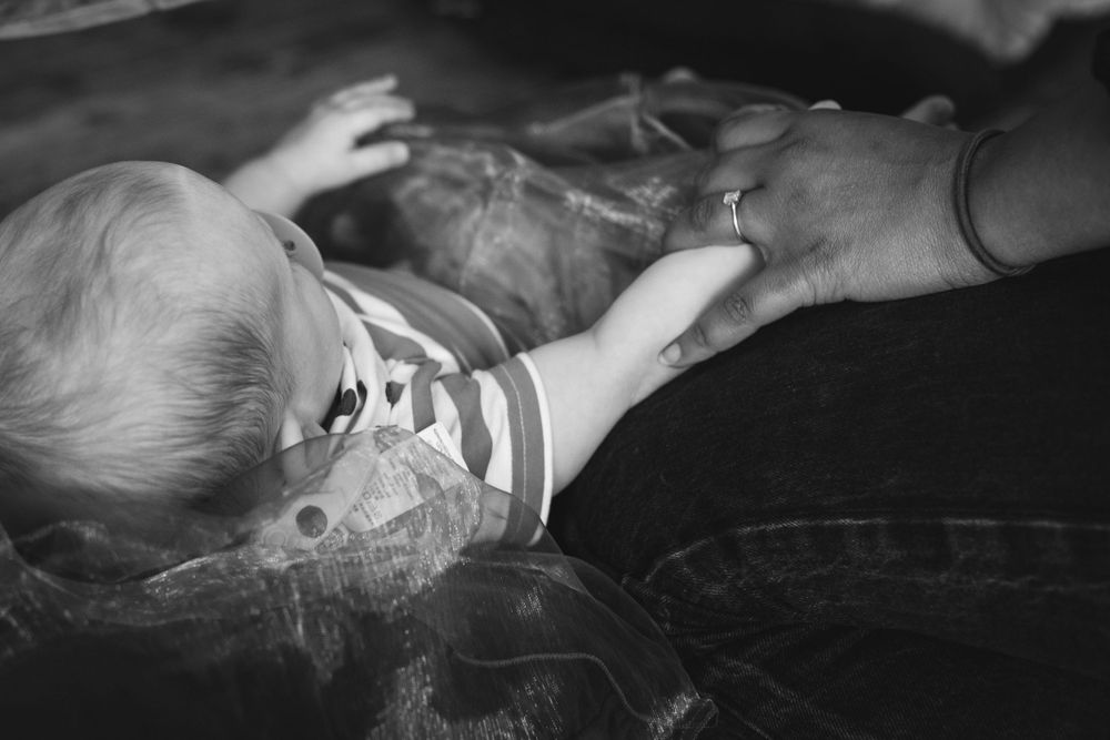 Black and white image of a baby reaching up during playtime.