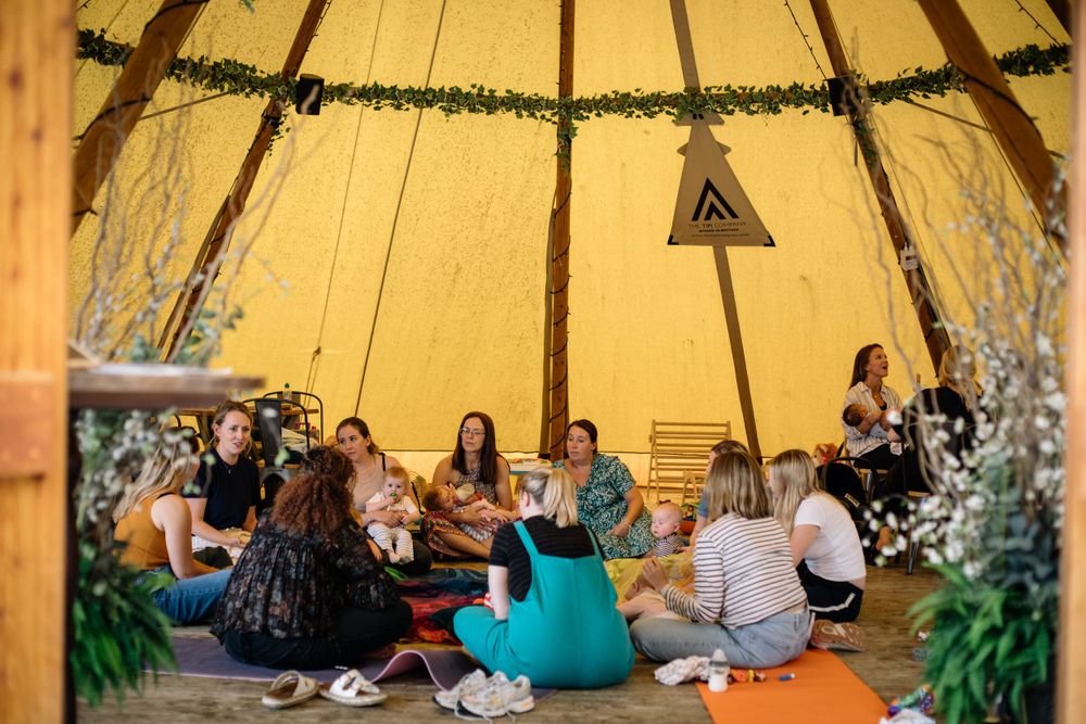 Parents and children gather in a decorated tipi-style tent for a group activity session.