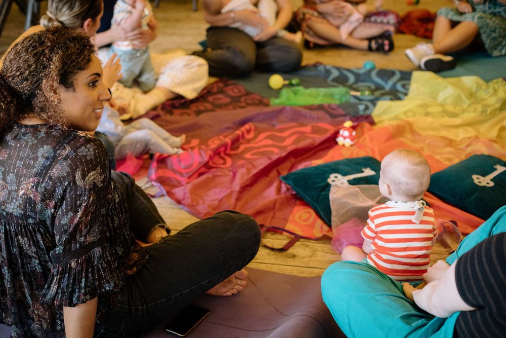 A sensory play session features colorful fabric mats where adults and children interact.