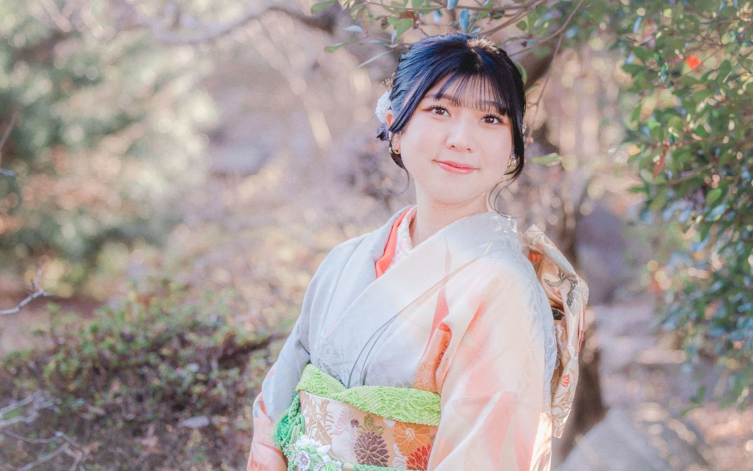 Person wearing traditional Japanese kimono poses among blooming spring foliage.