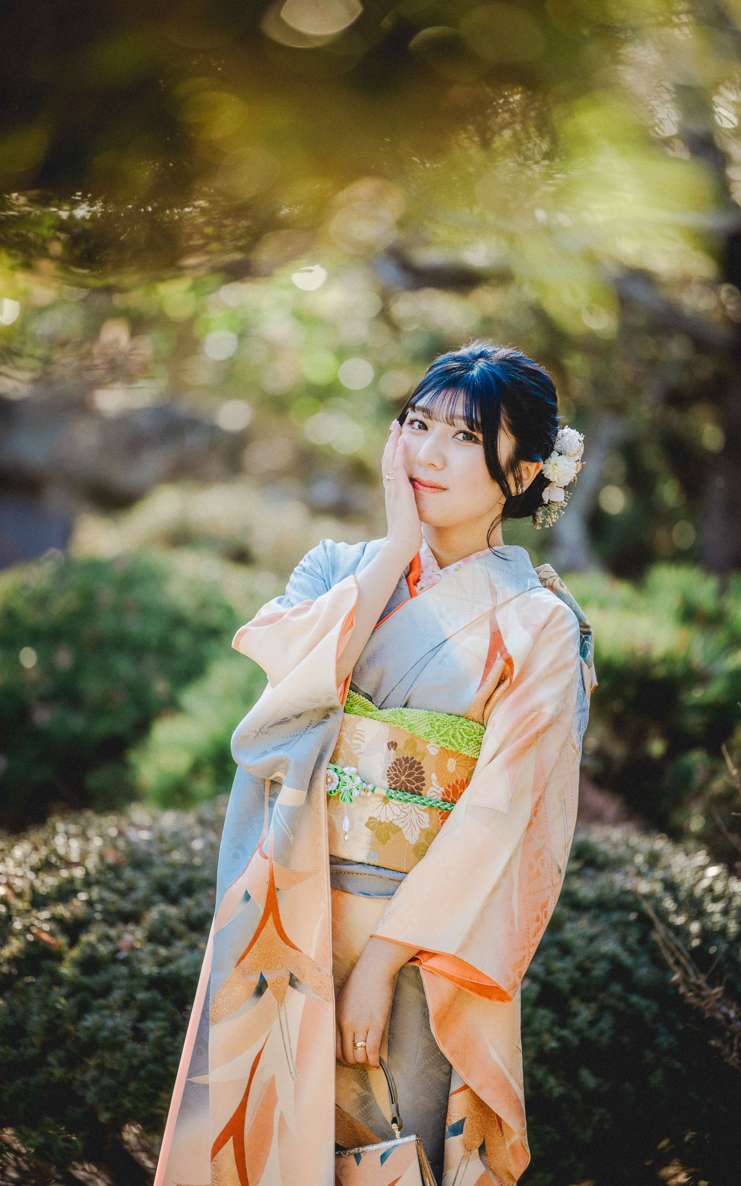 A woman in a traditional Japanese kimono poses gracefully in a garden with soft lighting and bokeh effects.