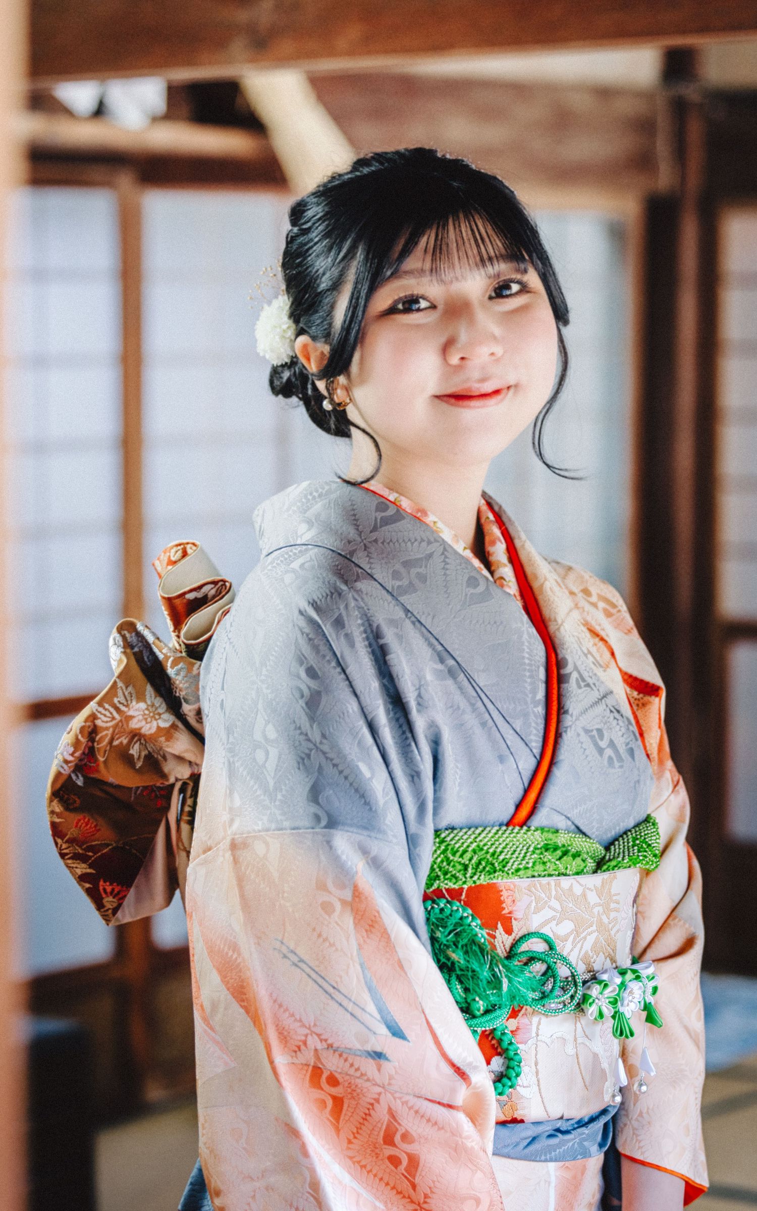 Traditional kimono in soft pastel colors with floral patterns worn in a Japanese interior setting.