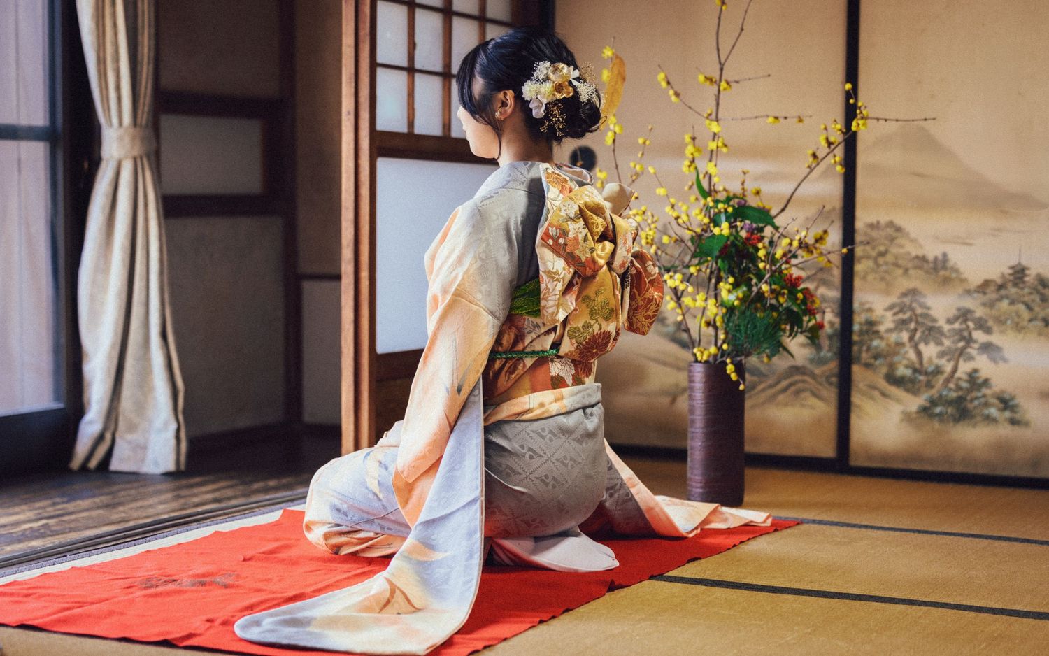 Traditional Japanese tea ceremony setting with floral arrangement and tatami mats.