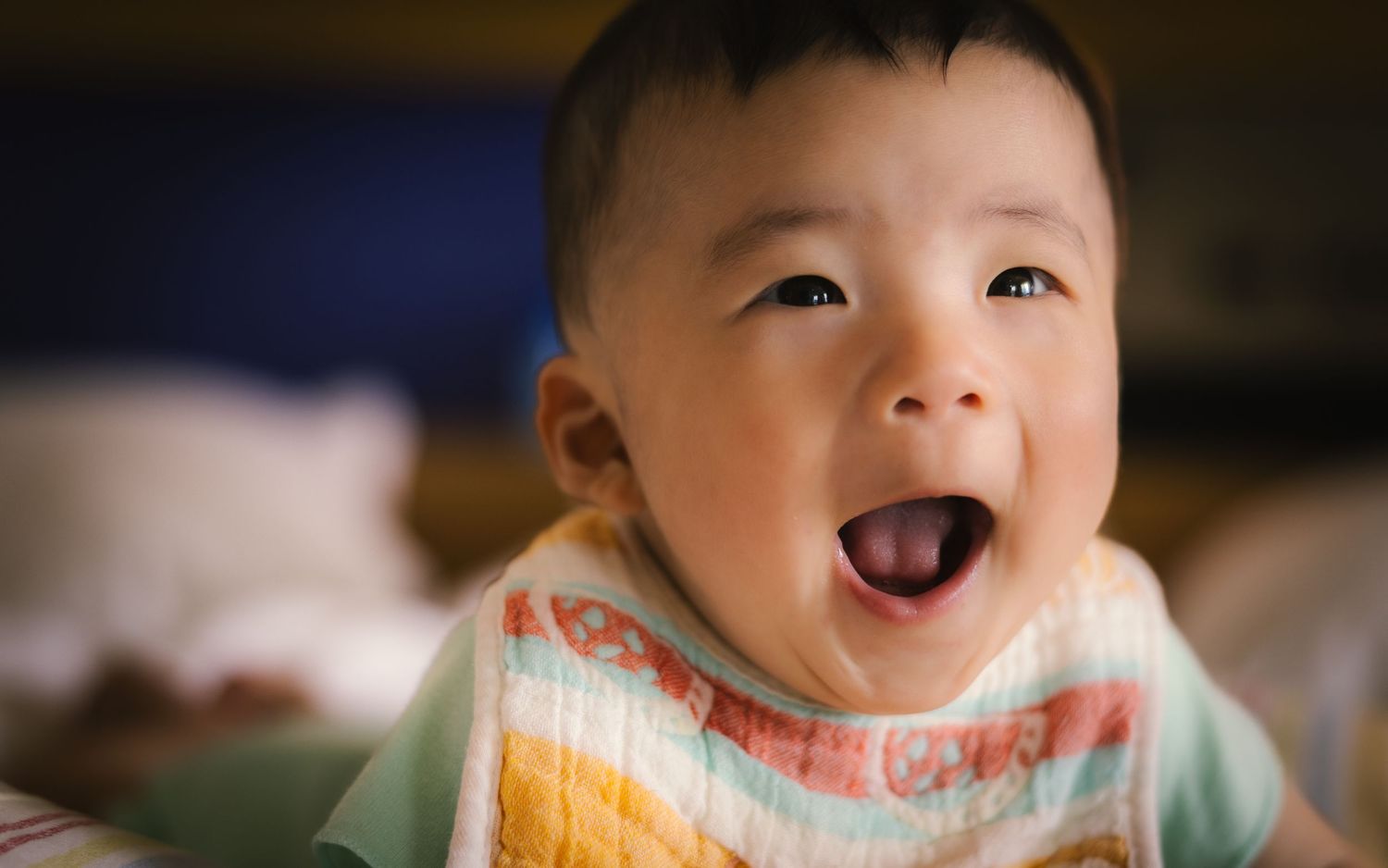 A happy baby with a bright smile wearing a yellow bib in a candid photography sequence.