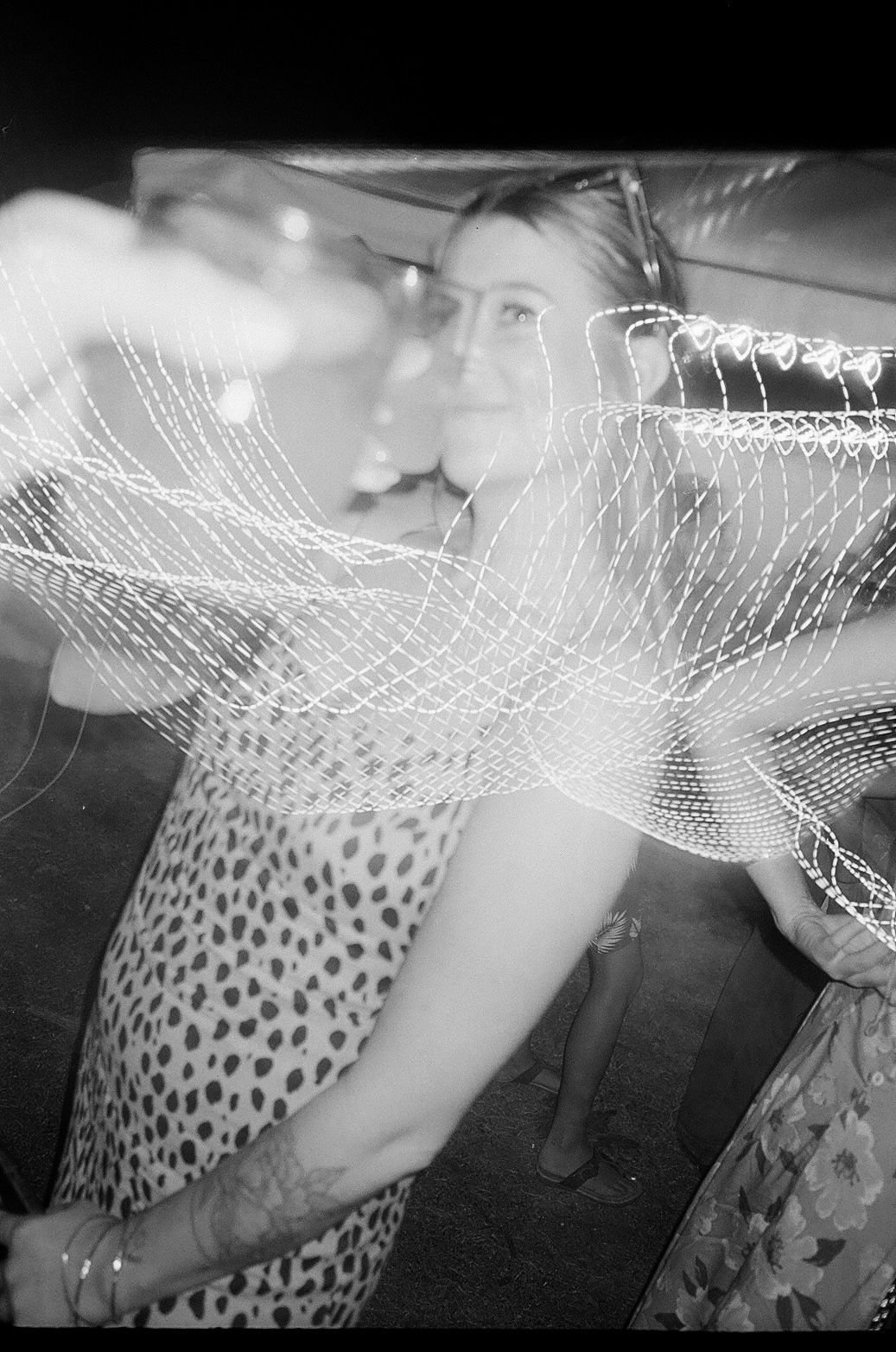 A blurred black and white photo showing a polka dot dress and slow shutter light effects.