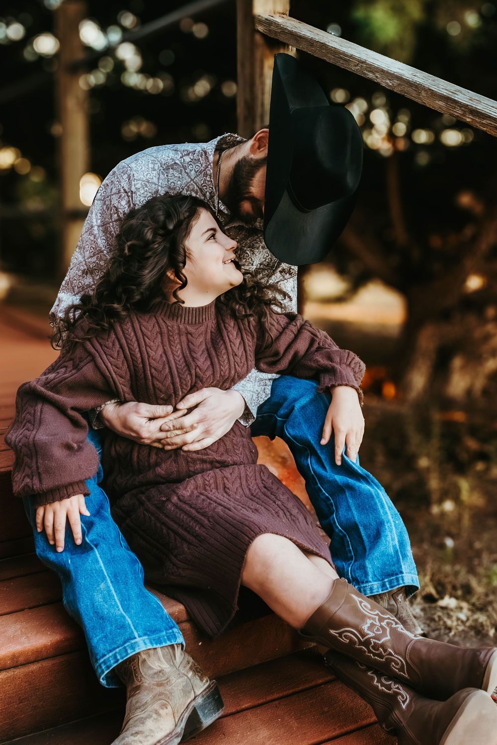 Couple in casual wear sharing intimate moments on wooden steps.