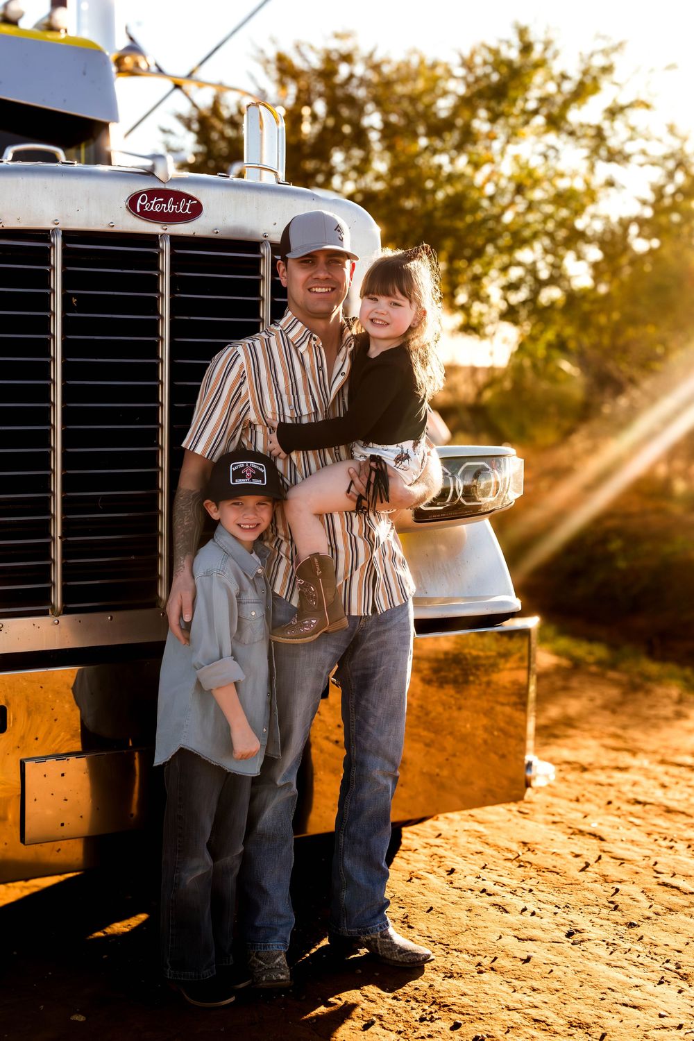 Golden hour photos of people posing beside a classic Peterbilt truck in a rural setting.