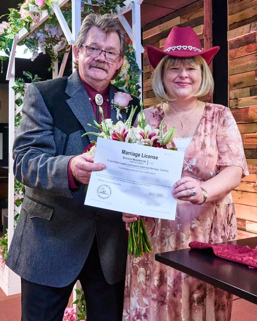 Couple showing off marriage license with pleased look on their faces.