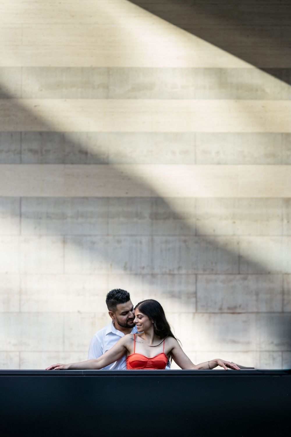 Intimate portrait with dramatic shadows and light on concrete architecture.