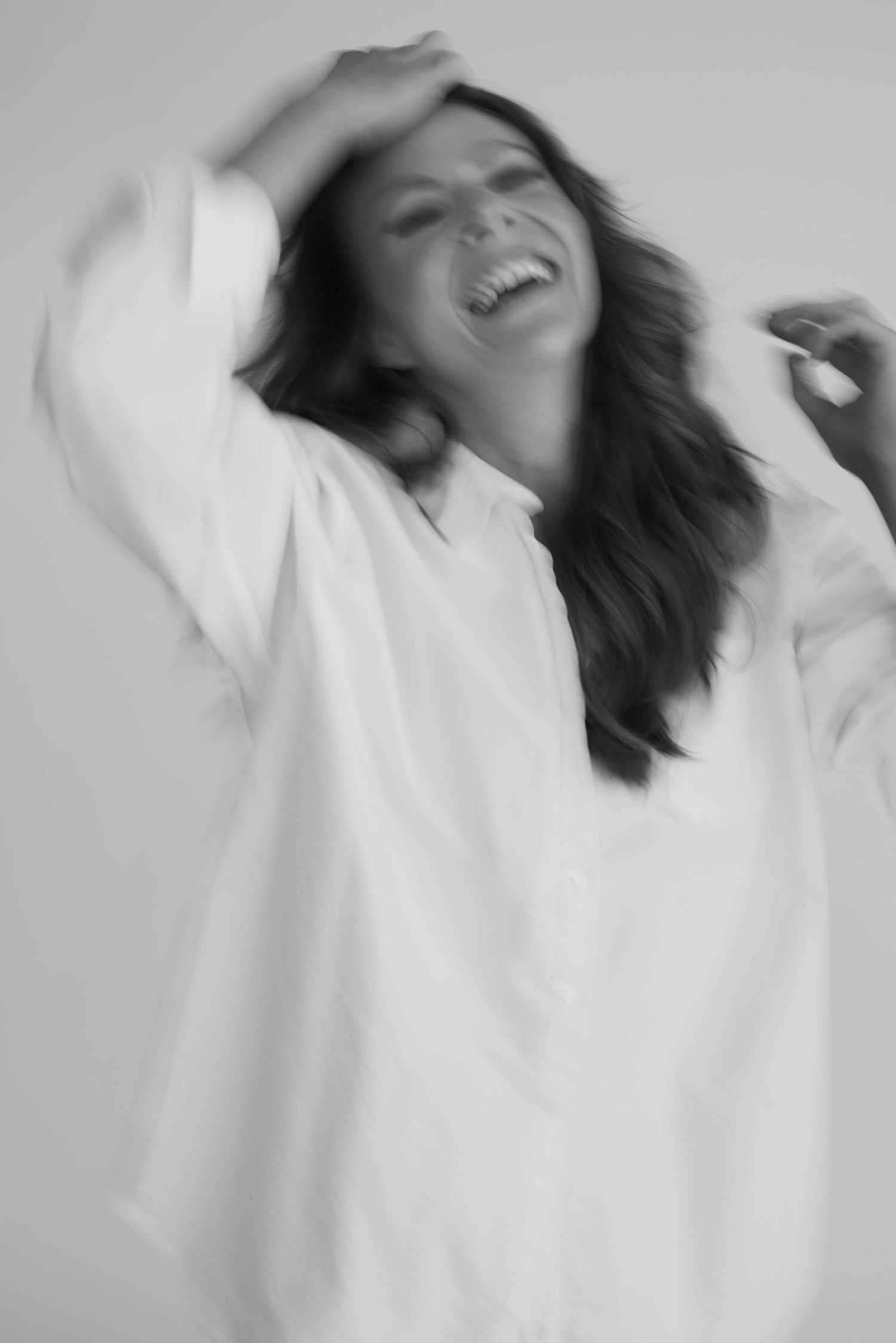 Black and white motion portrait showing dynamic movement in a white button-down shirt.