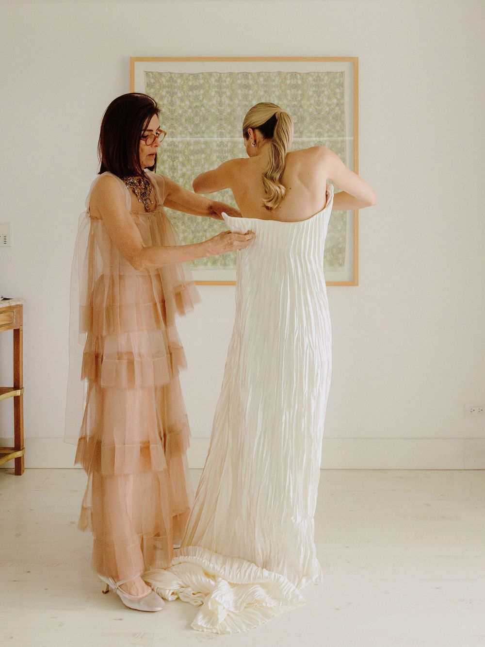 Two people share a moment while preparing in a bright white room with green wallpaper.