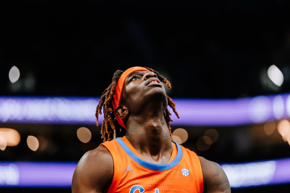 Florida Gators basketball player with orange braids and headband looks up during a college basketball game.