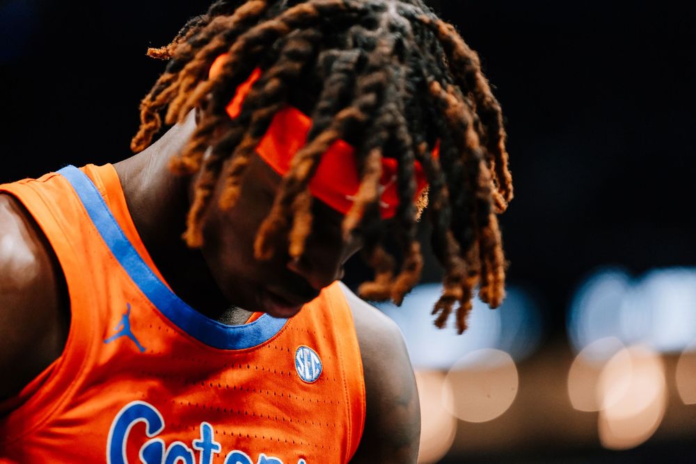 Close-up of Florida Gators basketball player with braids wearing orange SEC jersey looking downward.