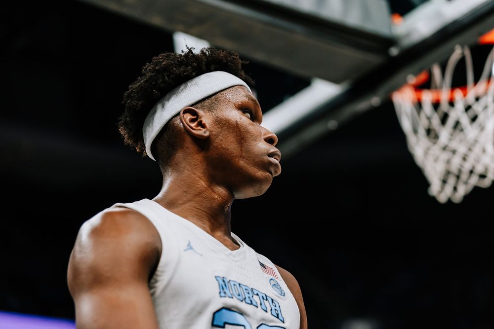North Carolina Tar Heels player wearing a white headband stands near the basket during a college basketball game.