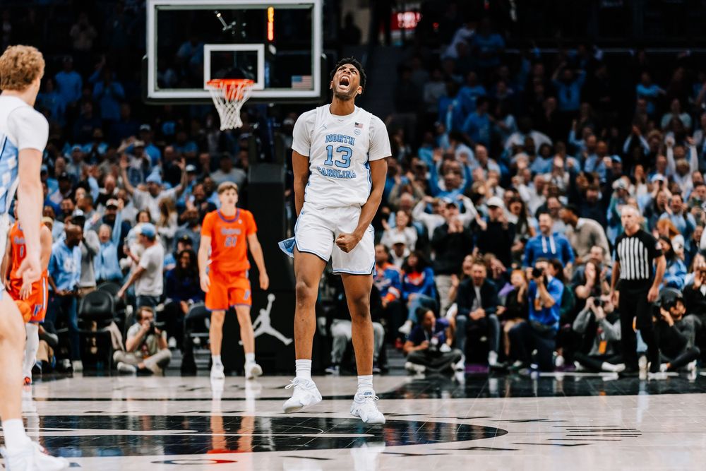UNC Tar Heels player #13 celebrates triumphantly on the basketball court during an intense college game.