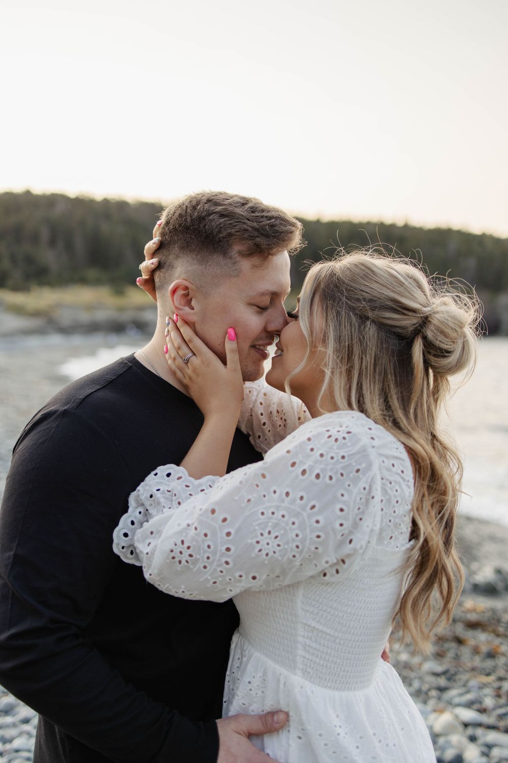 Intimate romantic moment between couple on a rocky beach at sunset.