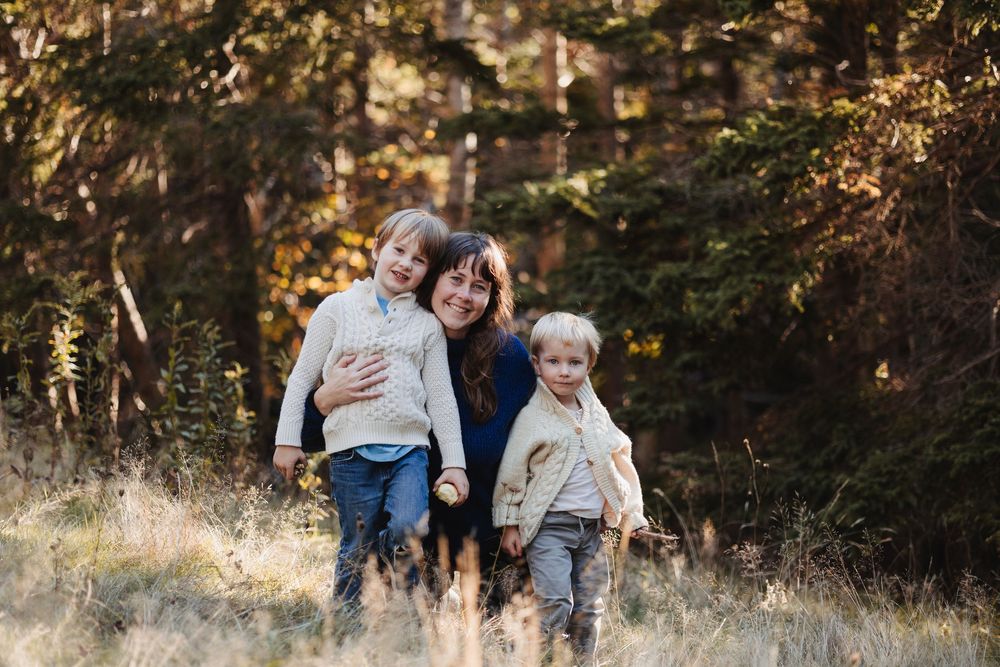 Family playing together in sunny autumn field near forest.