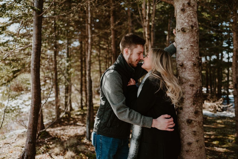 Intimate winter forest engagement photo among snow-covered trees.