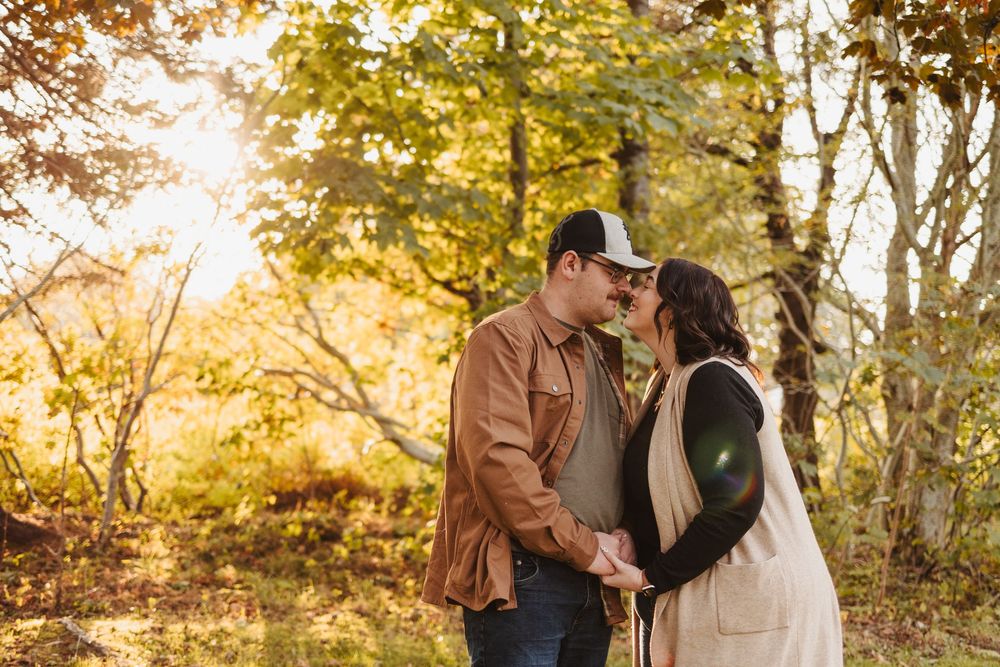 Romantic autumn engagement photo in golden sunlit forest.