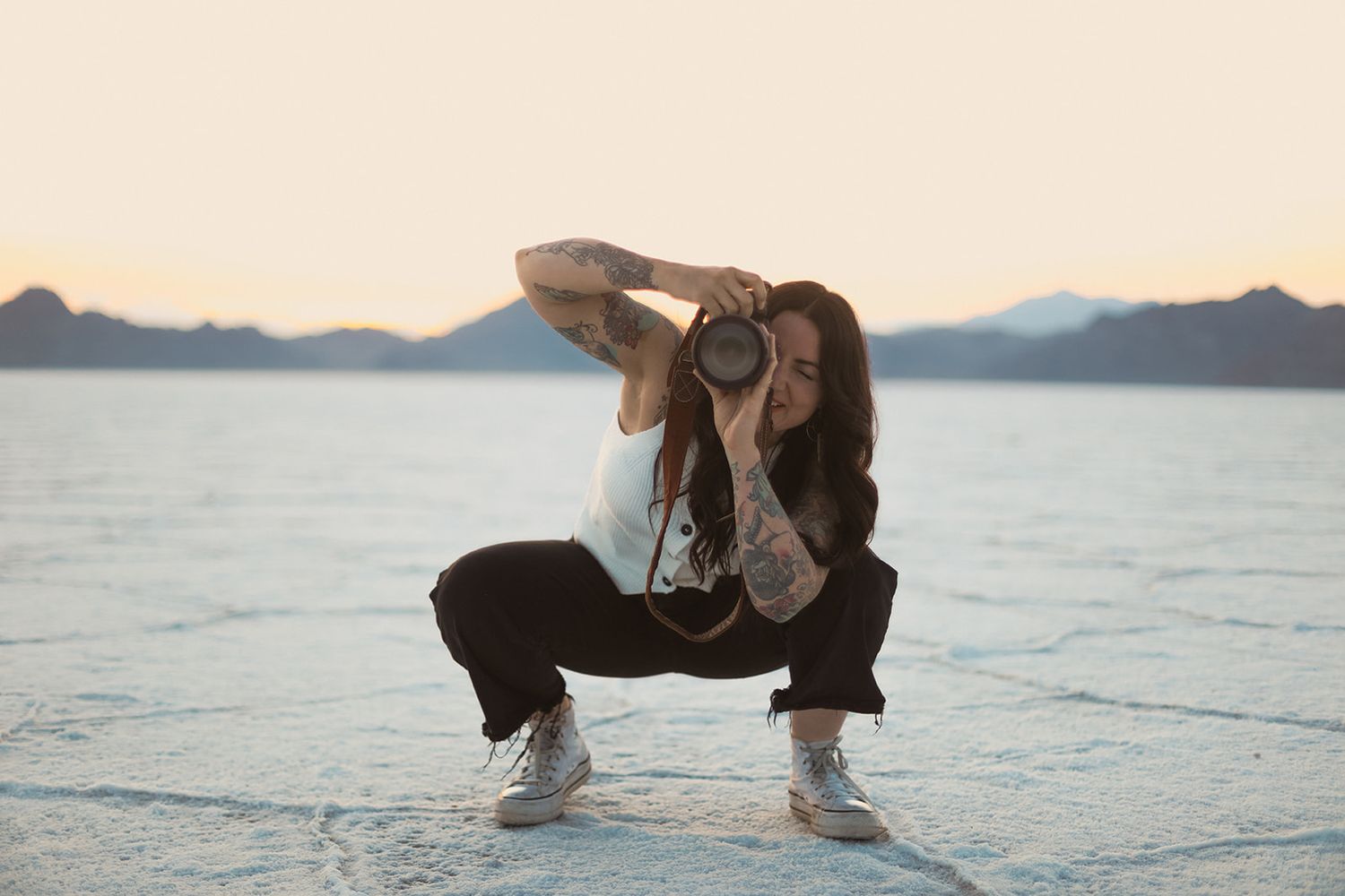 A color photo showing Lauren from Terra Firma Photography smiling with her camera on a salt flat landscape.