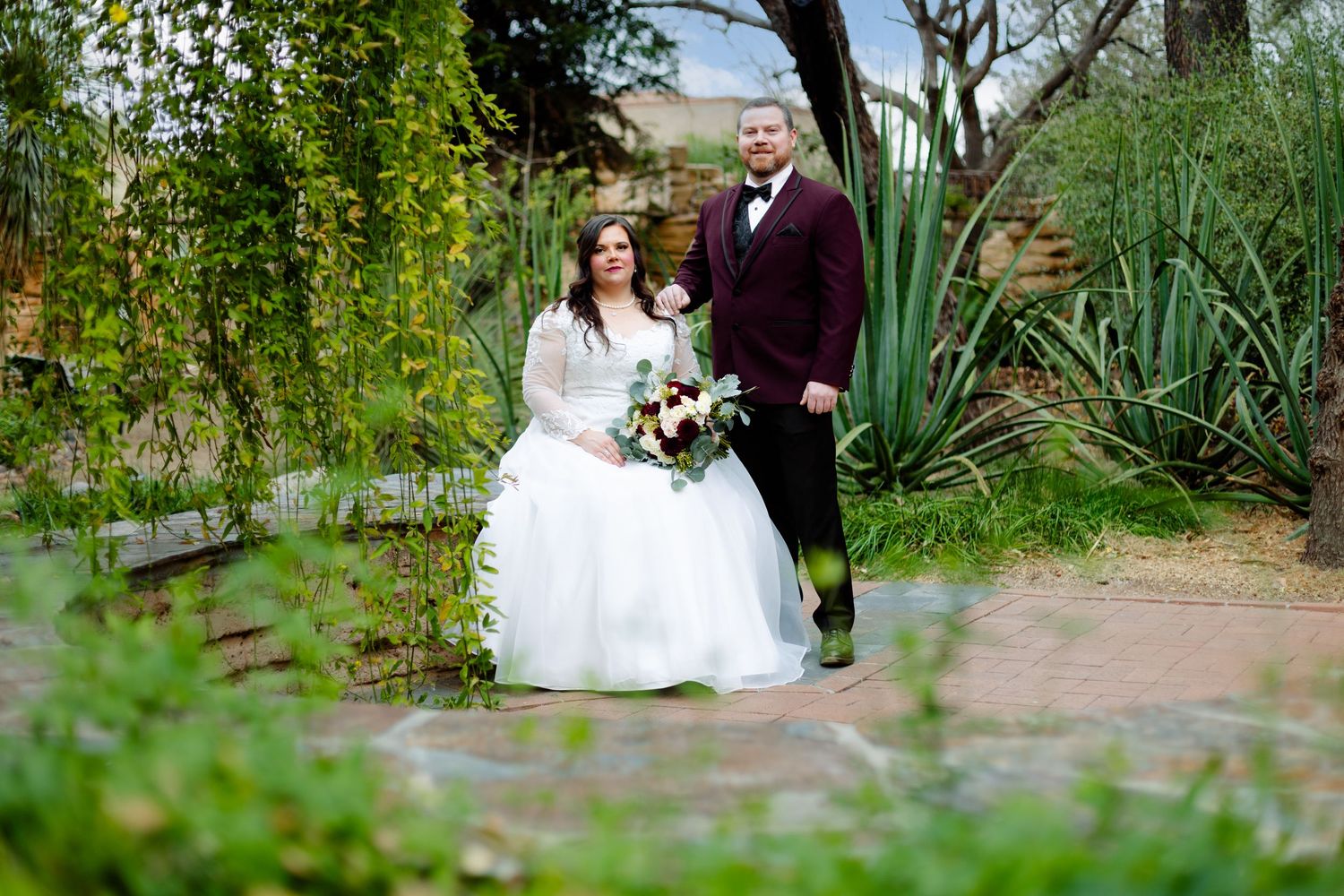 A wedding couple shares an intimate moment in a lush garden setting.