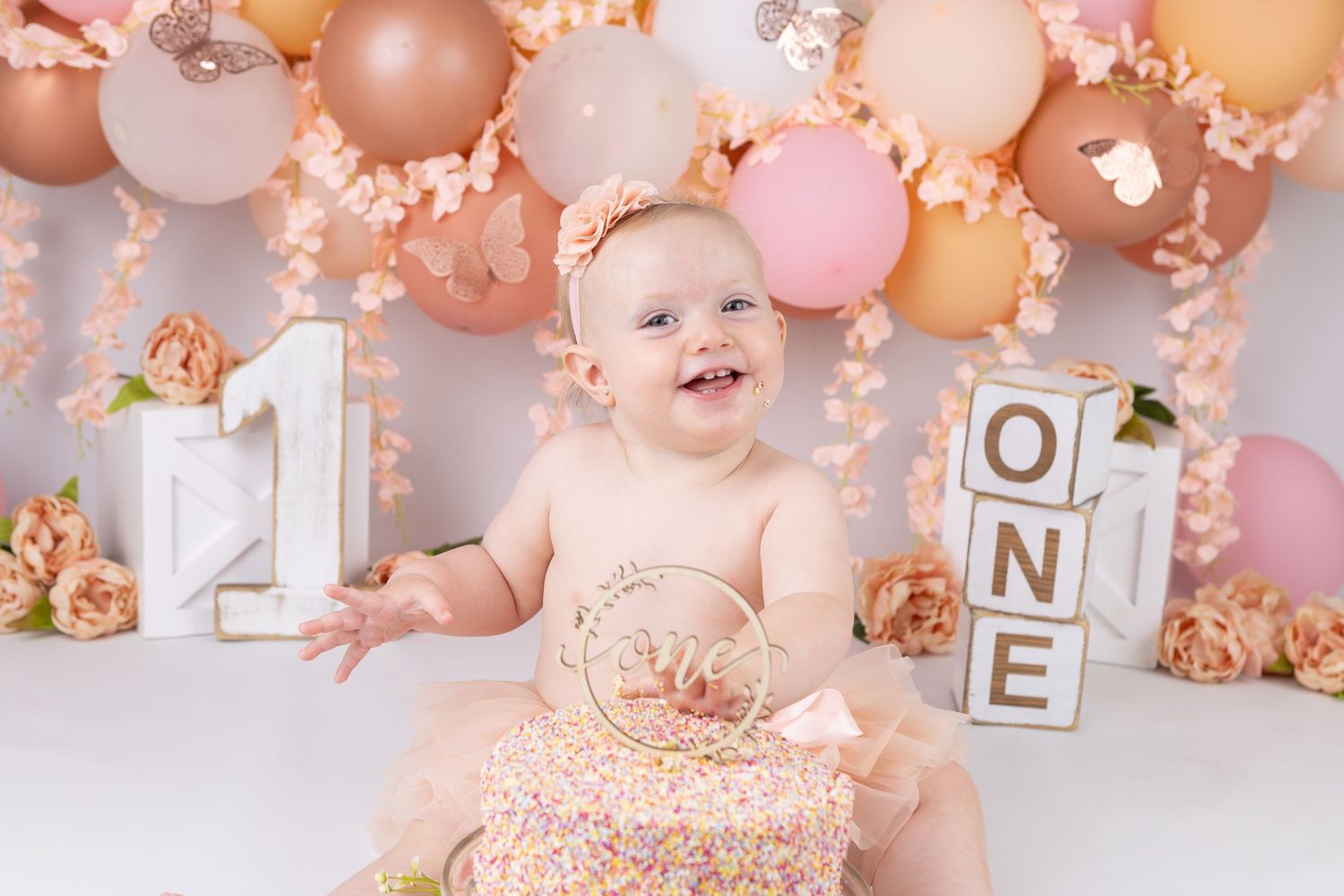Baby's first birthday setup with pink balloons and letter blocks.