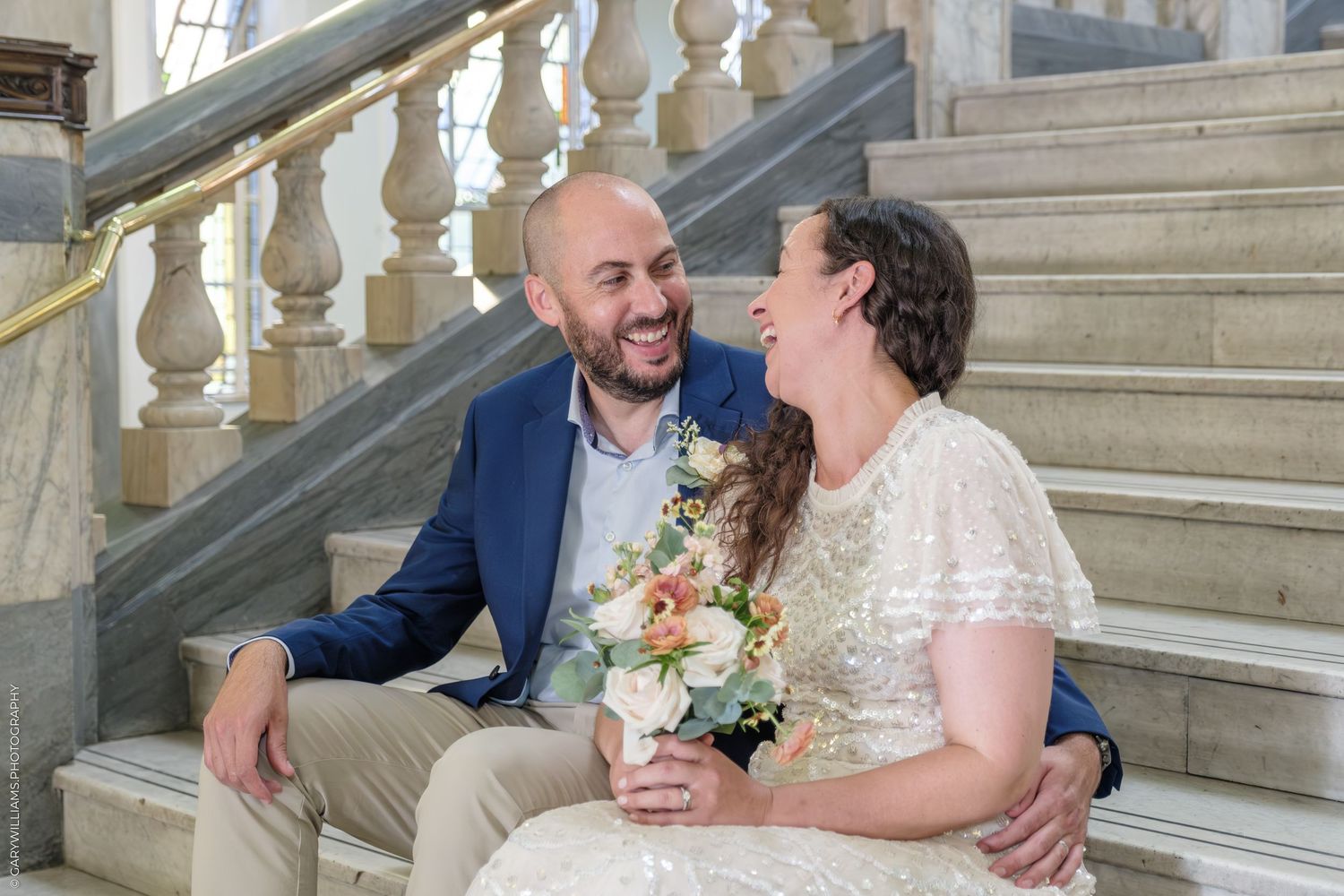 Wedding celebration on ornate stone steps with decorative white balustrades.