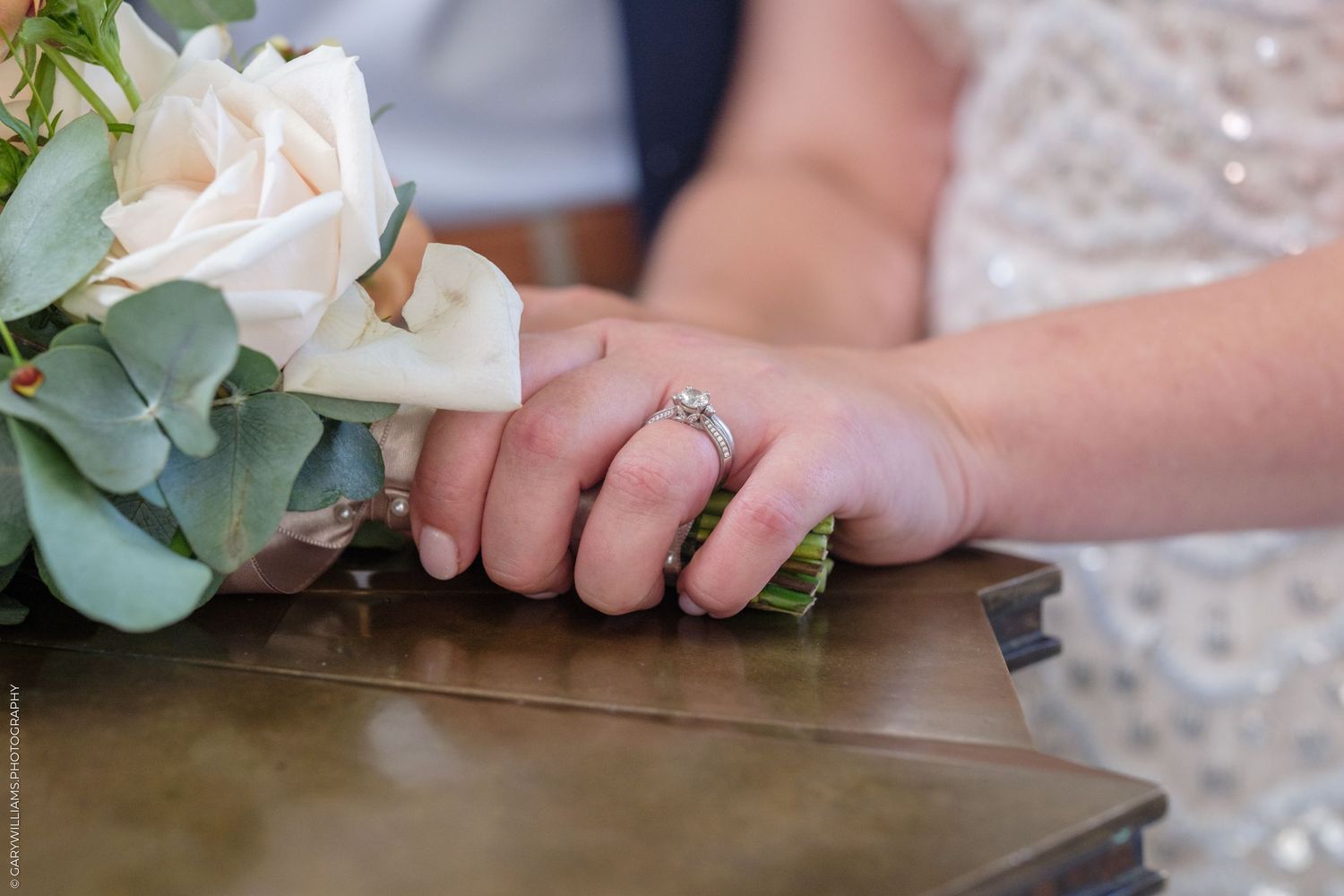A white rose bouquet rests on a rustic wooden table during a wedding celebration.