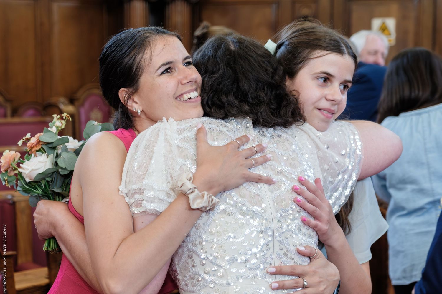 A wedding celebration showing warm hugs and joyful embraces between attendees in a church setting.