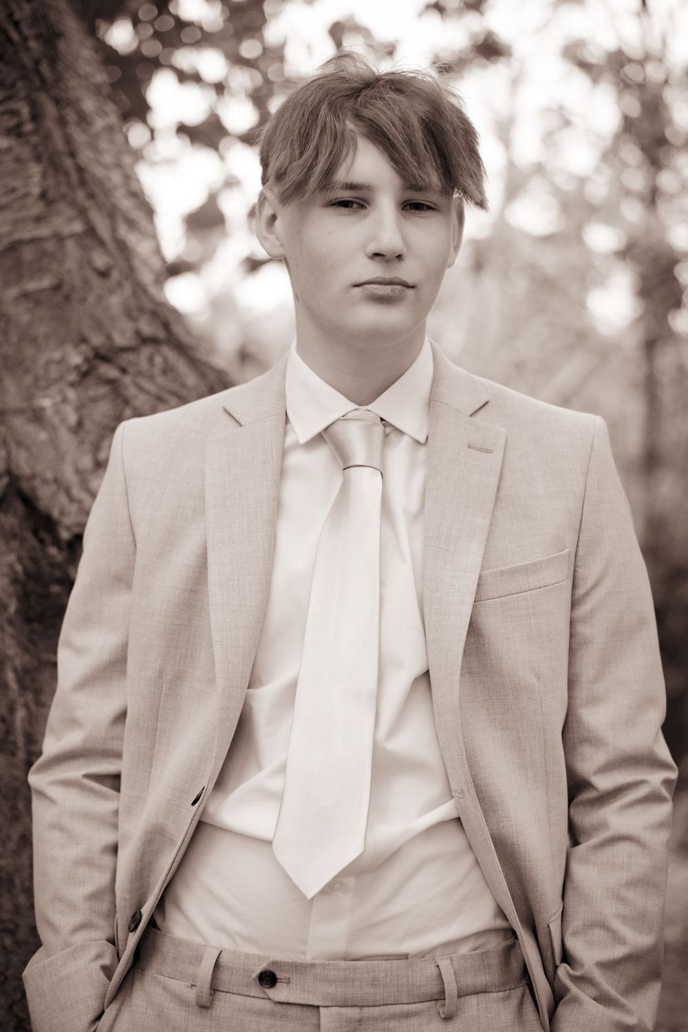 A series of monochromatic fashion portraits showing someone in a light-colored suit and tie outdoors.