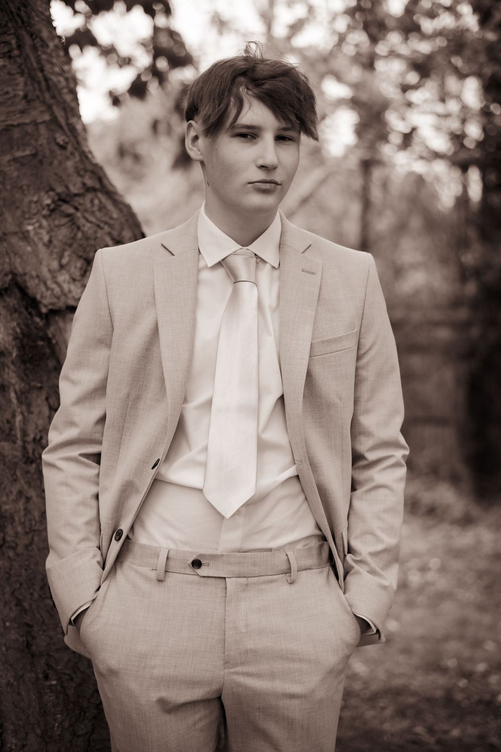 Connected portrait shots of a person wearing a formal light suit and tie against a blurred natural background.