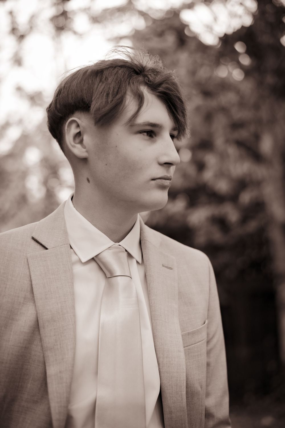 A sepia-toned series of four profile shots showing someone in a light colored suit looking to the side.