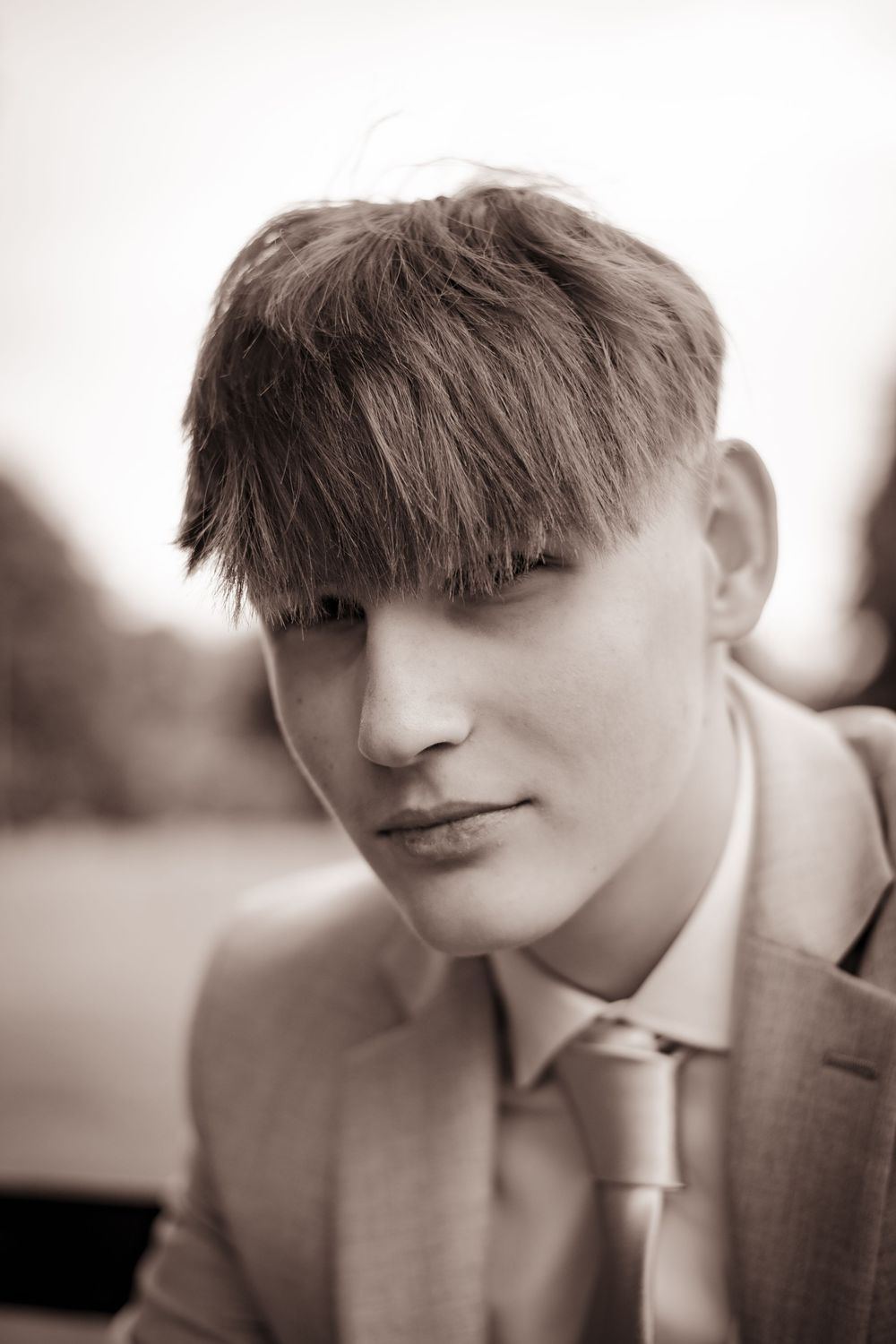 Artistic black and white close-up portrait showcasing a modern hairstyle and formal attire.