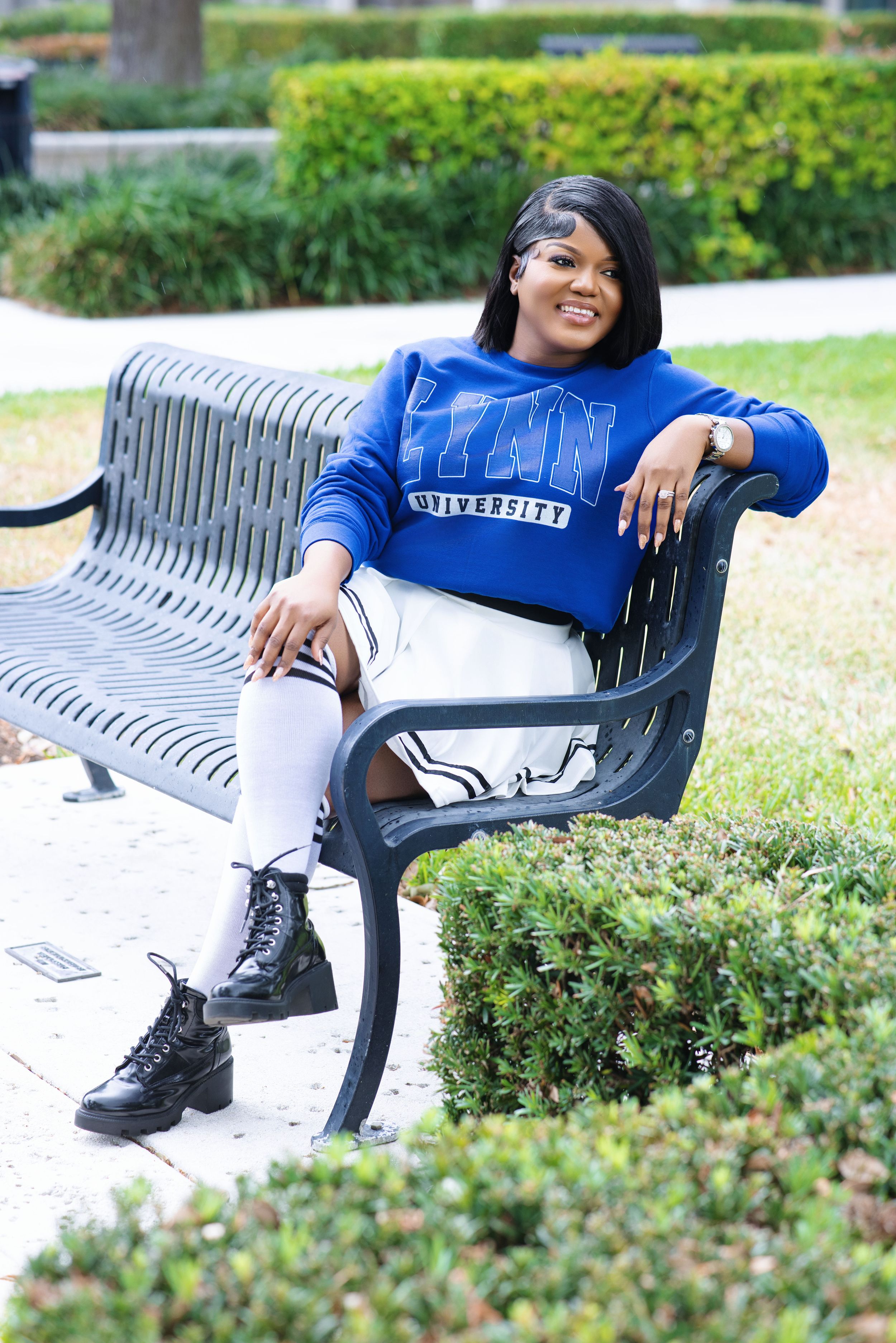 Young woman in Lynn University sweatshirt sitting on bench outdoors.