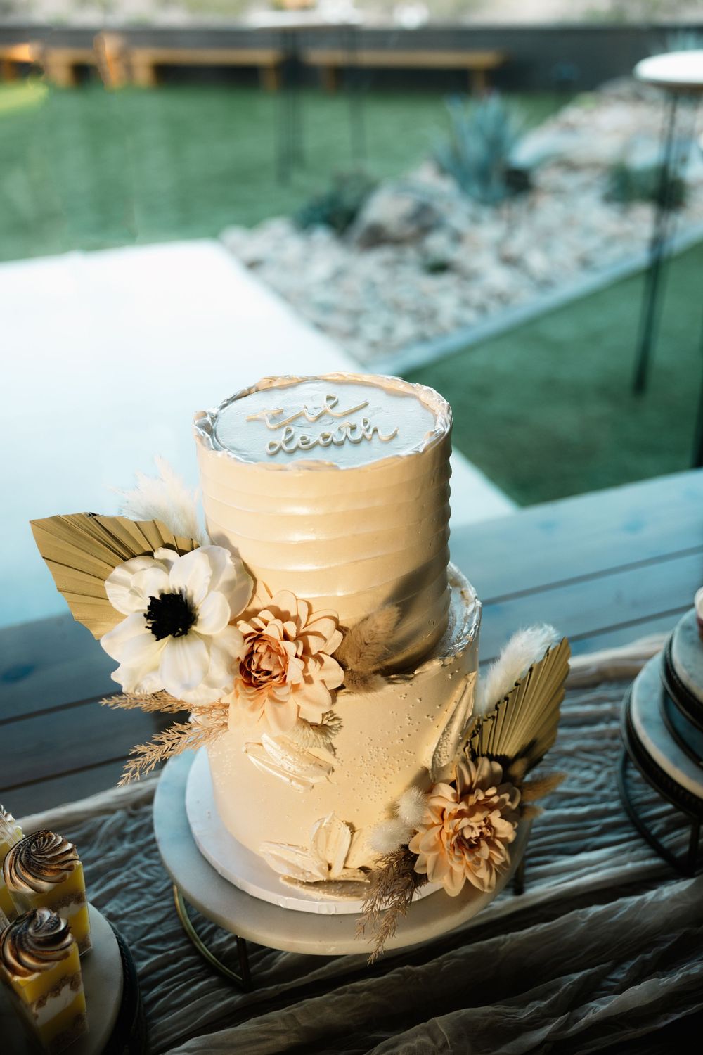 An elegant white wedding cake decorated with gold accents and floral details.