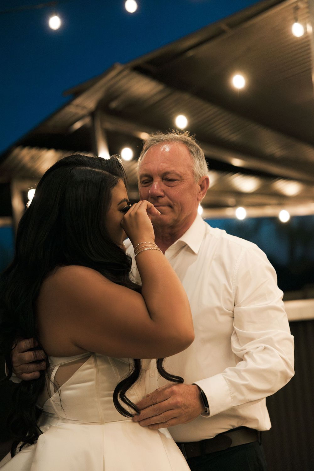 A tender dance moment captured under warm evening lighting at a wedding reception.