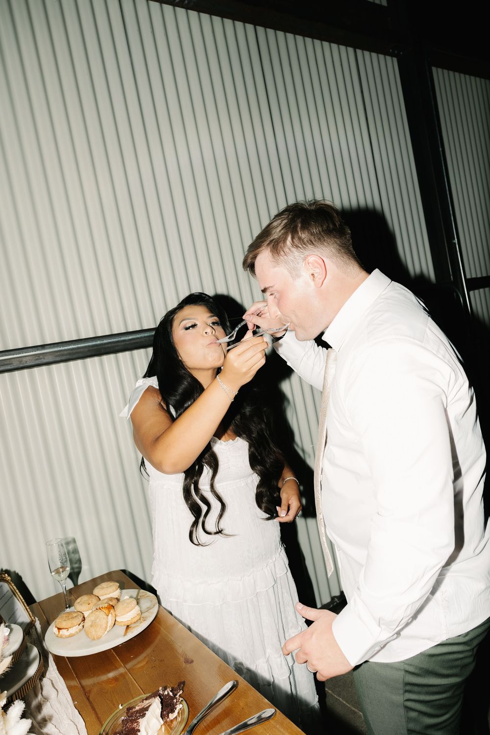 Wedding guests enjoying cake and desserts at a reception table.