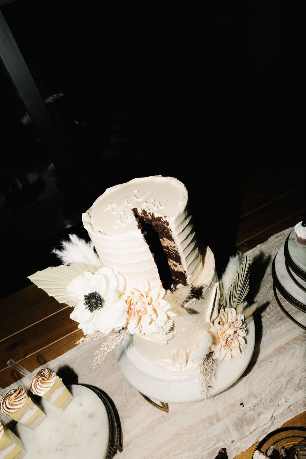 White wedding cake with floral decorations displayed on a wooden table.