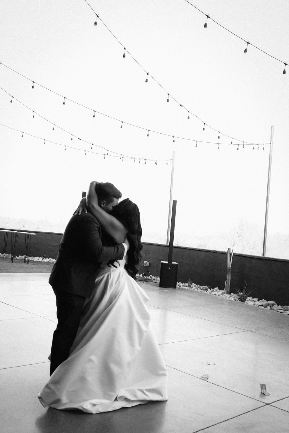 A couple performs an intimate slow dance in black and white photography.