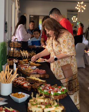 Woman in floral dress serving herself from an elaborate charcuterie and appetizer buffet table.