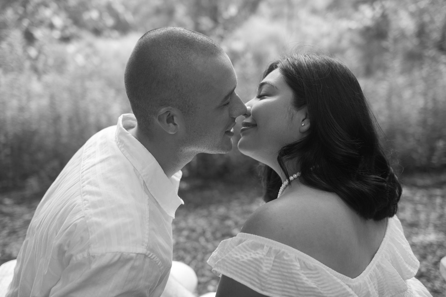 Intimate romantic moment captured in soft natural lighting outdoors.