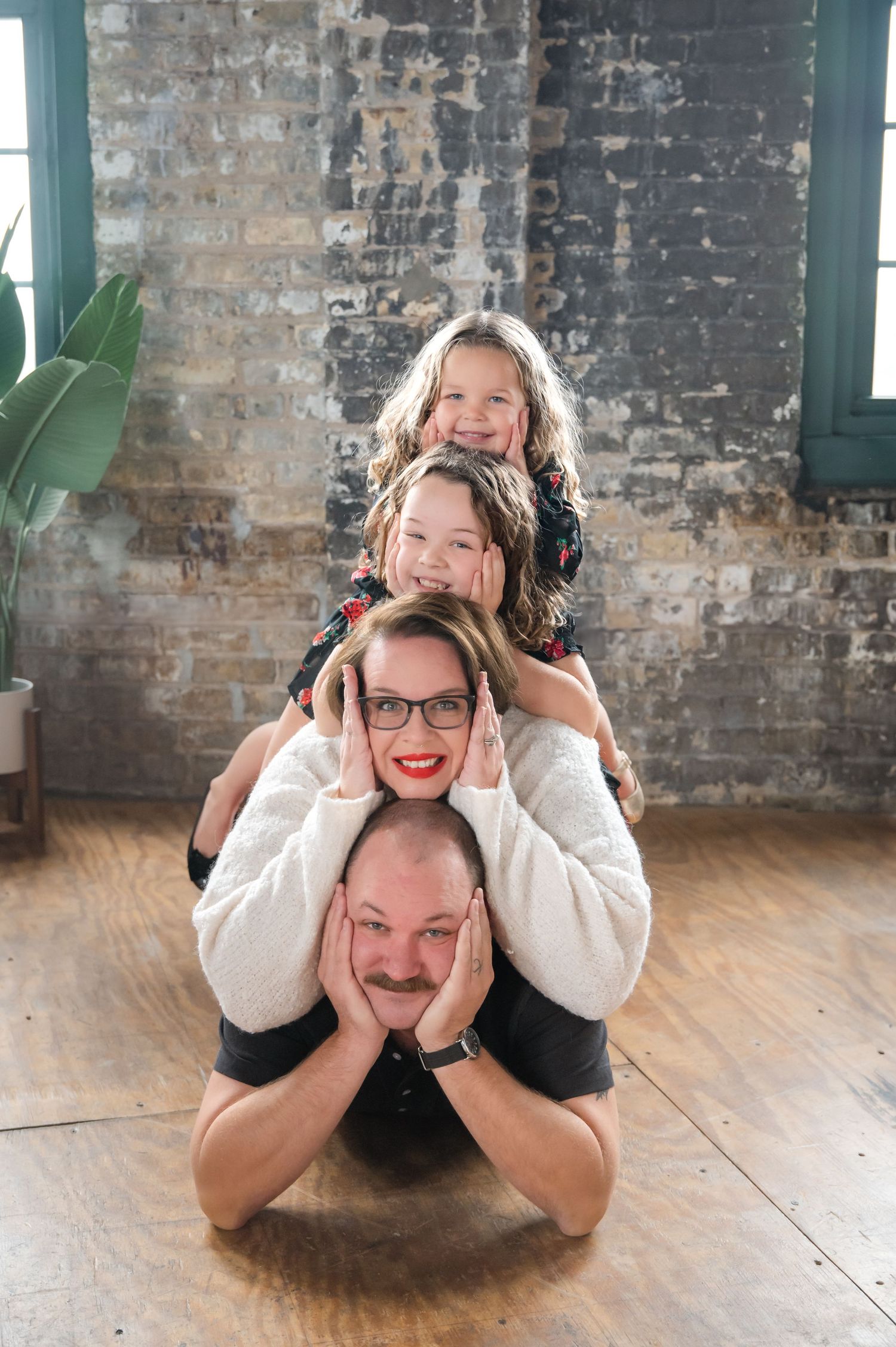 Three playful photos show a parent and child lying on a wooden floor making silly faces while wearing black headphones.