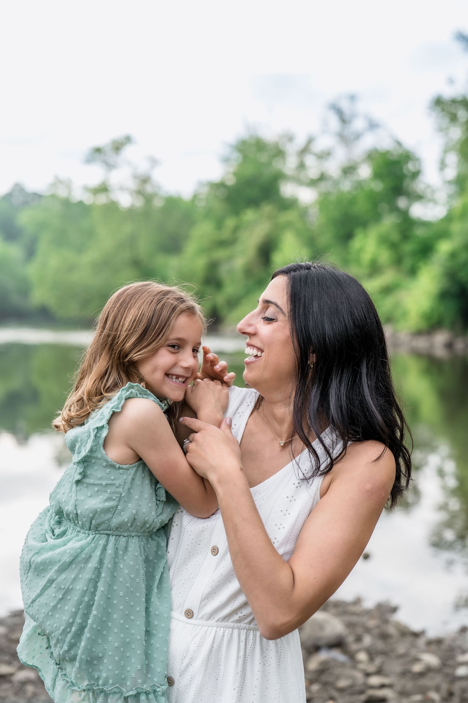 Two people share a sweet moment while laughing together by a waterfront in a series of candid outdoor photos.