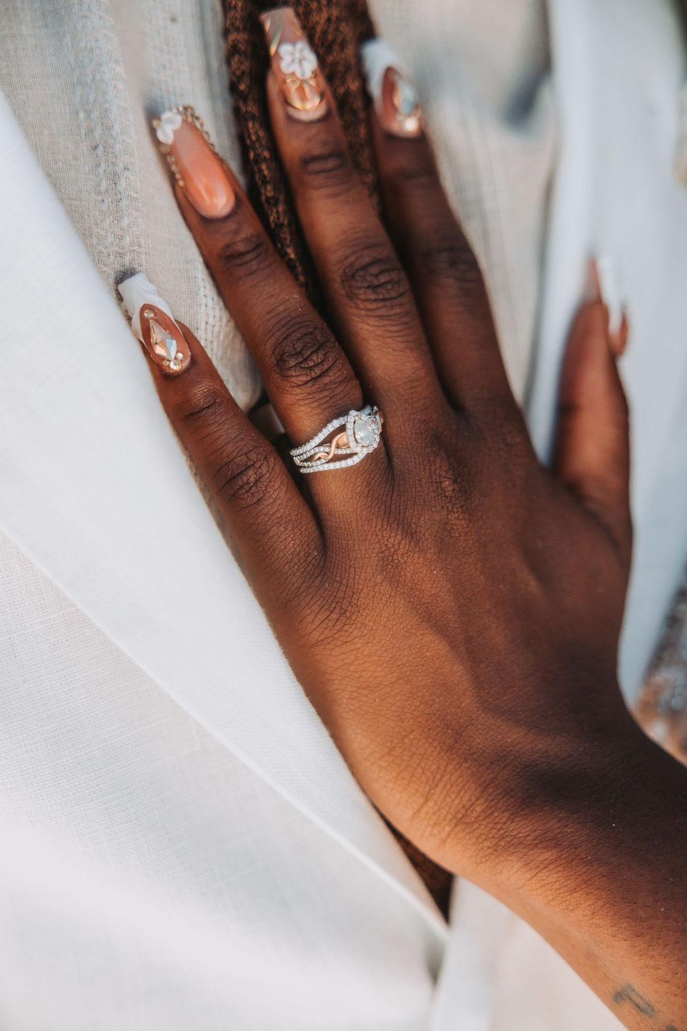 Close-up of a black hand wearing an elegant solitaire diamond engagement ring on a white background.