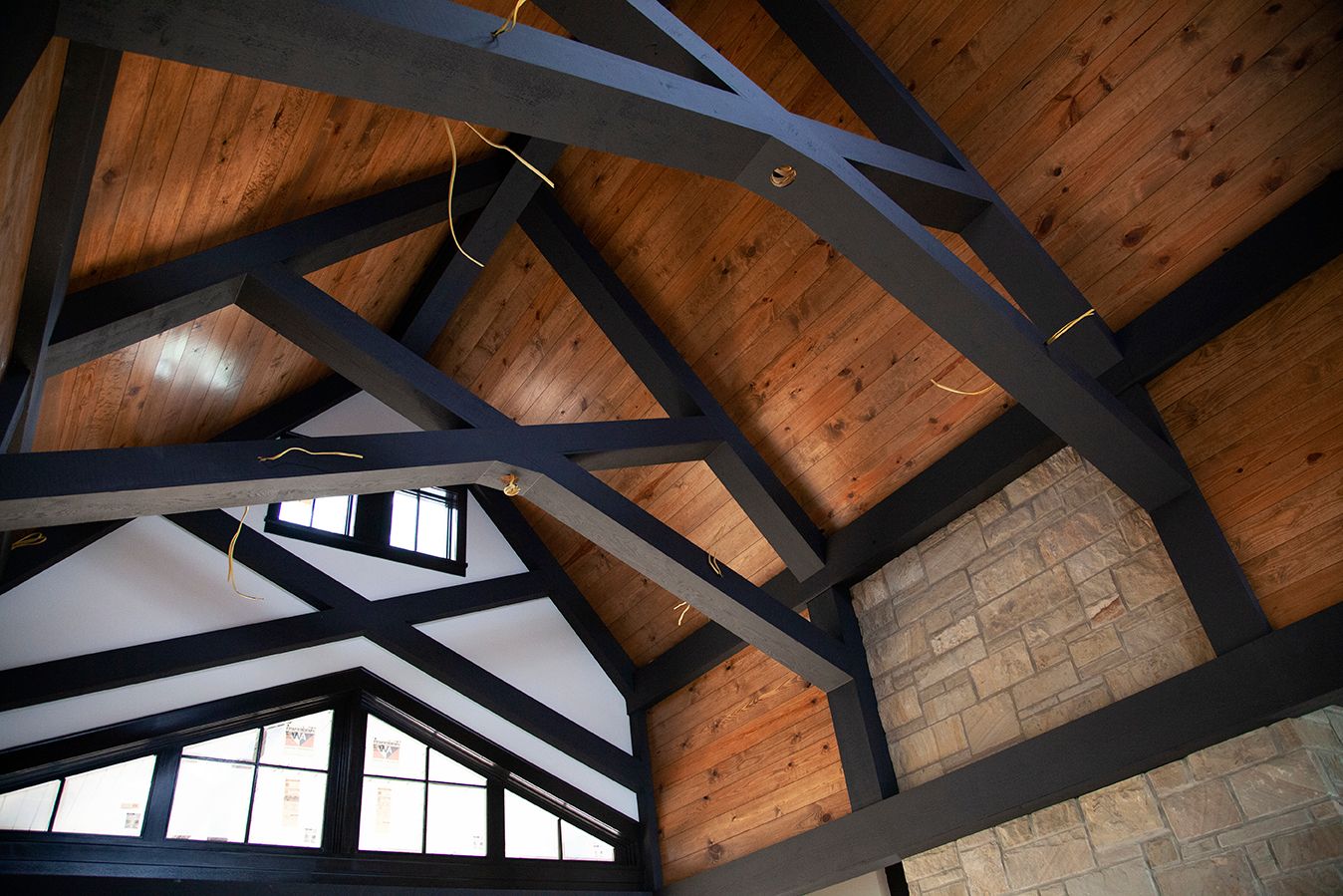 Architectural detail of wooden beams and rafters on a vaulted ceiling with natural lighting.